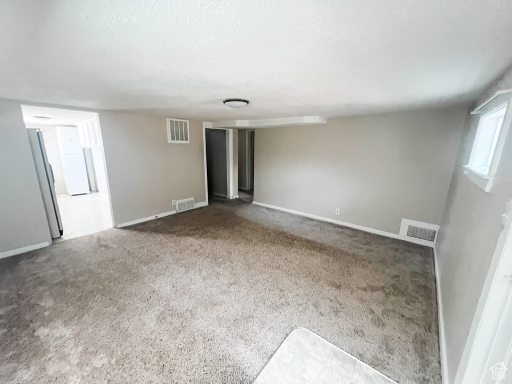 Carpeted spare room featuring baseboards and a textured ceiling