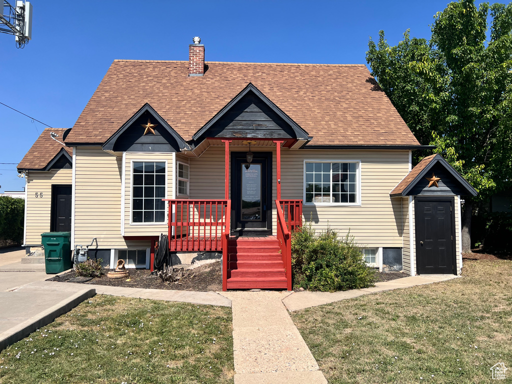 View of front of house with a front lawn, roof with shingles, and a chimney