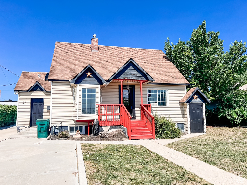 Bungalow with a porch, a front lawn, a shingled roof, and a chimney