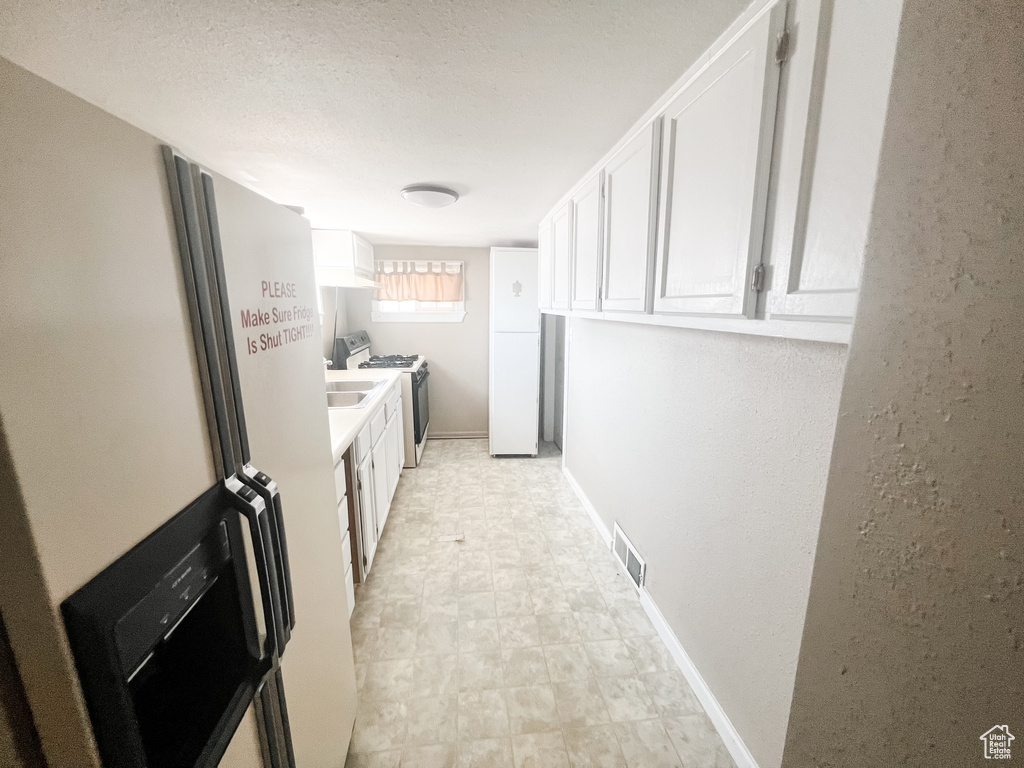 Kitchen with white appliances, white cabinetry, light flooring, and light countertops