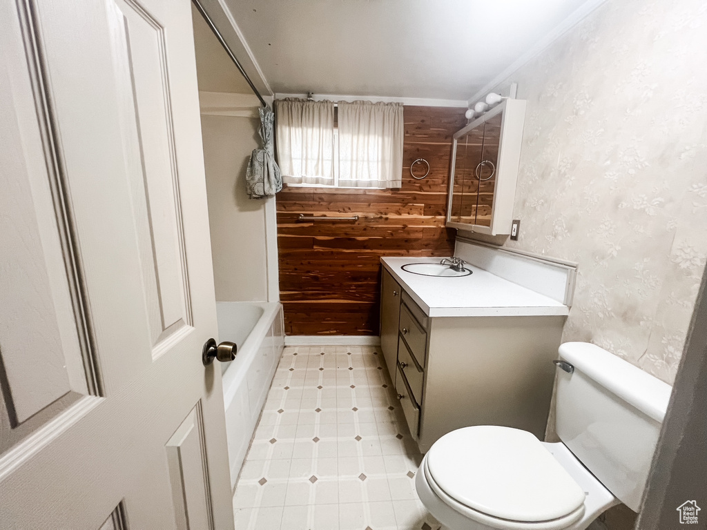 Full bath with vanity, tile patterned floors, crown molding, wooden walls, and shower / bath combination