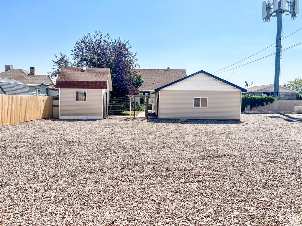 Rear view of property featuring a storage shed and roof with shingles