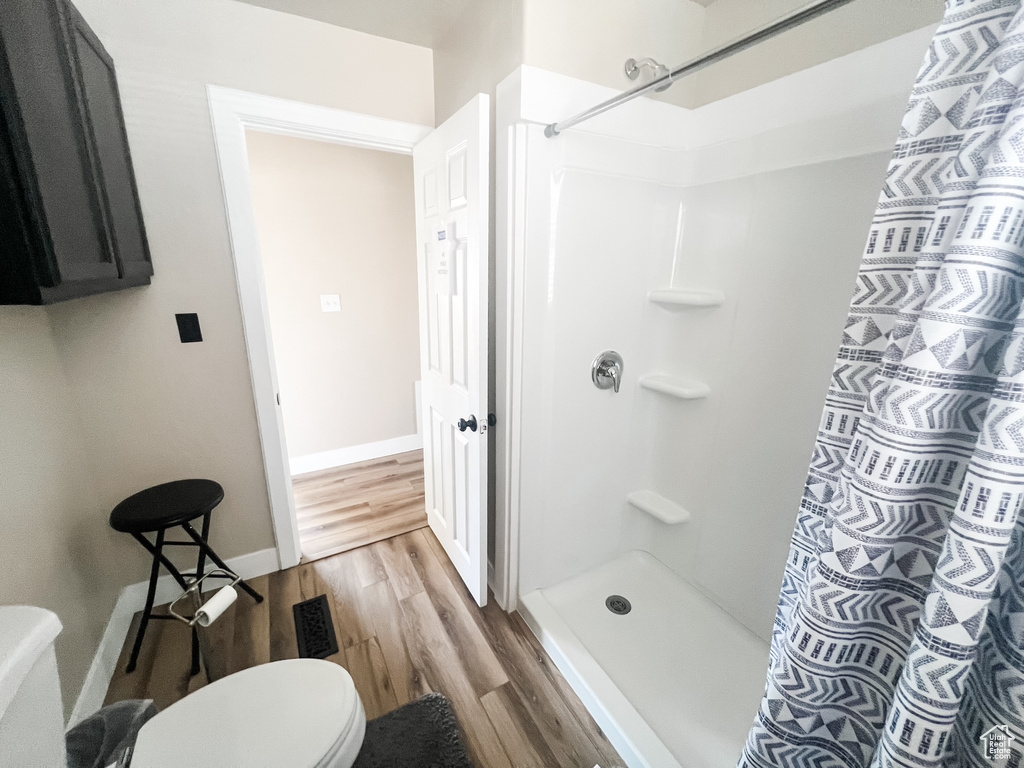 Full bath with wood finished floors and a shower with curtain