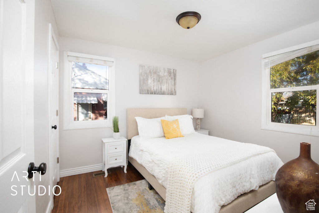 Bedroom with multiple windows and dark hardwood / wood-style floors