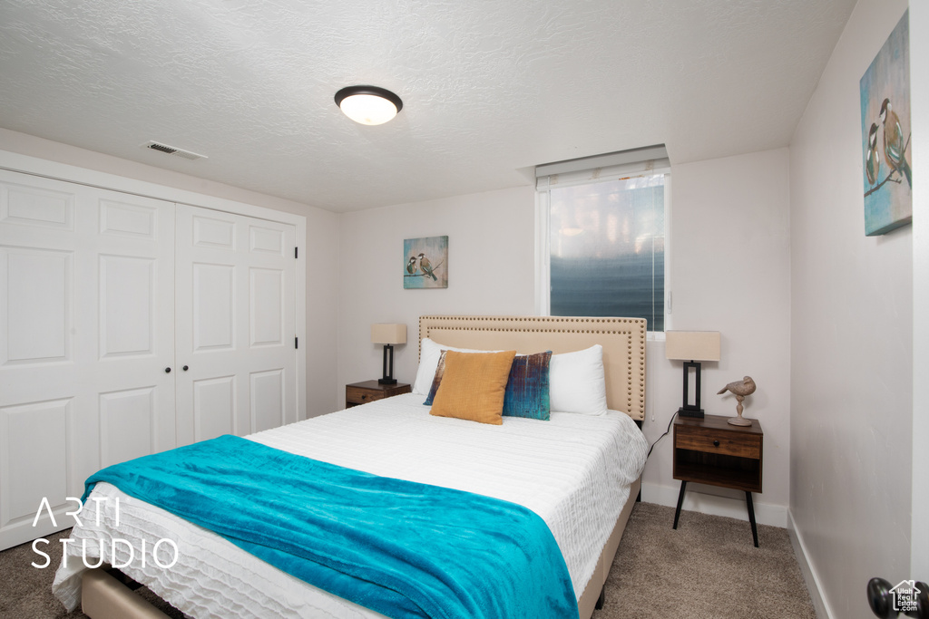 Bedroom featuring carpet, a textured ceiling, and a closet