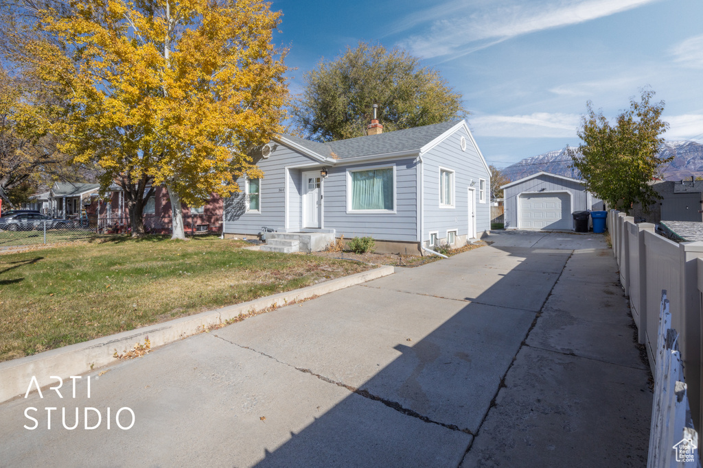 View of front facade with a mountain view, a garage, an outdoor structure, and a front yard