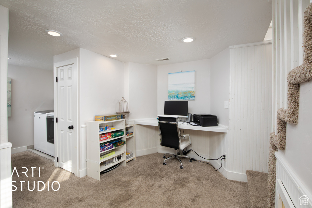 Office with a textured ceiling, built in desk, washer / clothes dryer, and light colored carpet