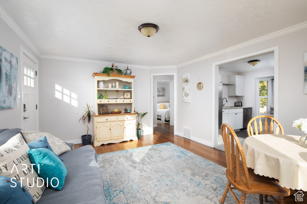 Living room featuring wood-type flooring, plenty of natural light, and crown molding