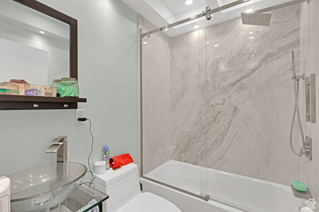 Full bathroom featuring shower / bath combination with glass door, toilet, and sink