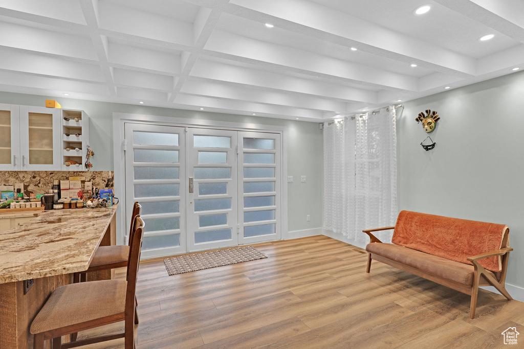 Dining space with coffered ceiling, beam ceiling, and light hardwood / wood-style flooring