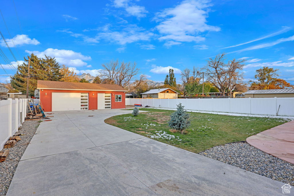 View of front facade with a garage, a front lawn, and an outdoor structure