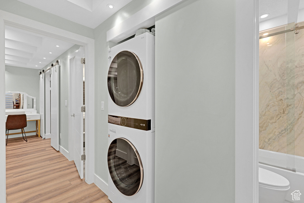 Laundry area with stacked washer / drying machine and light hardwood / wood-style floors