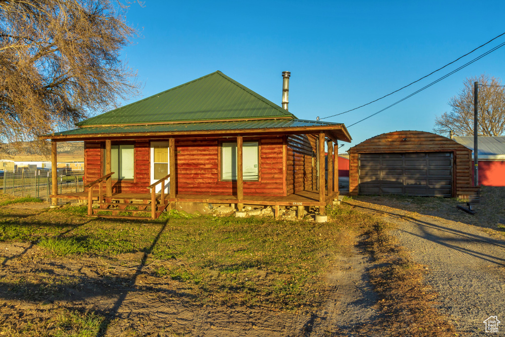 Log home featuring a garage, an outbuilding, and a front yard