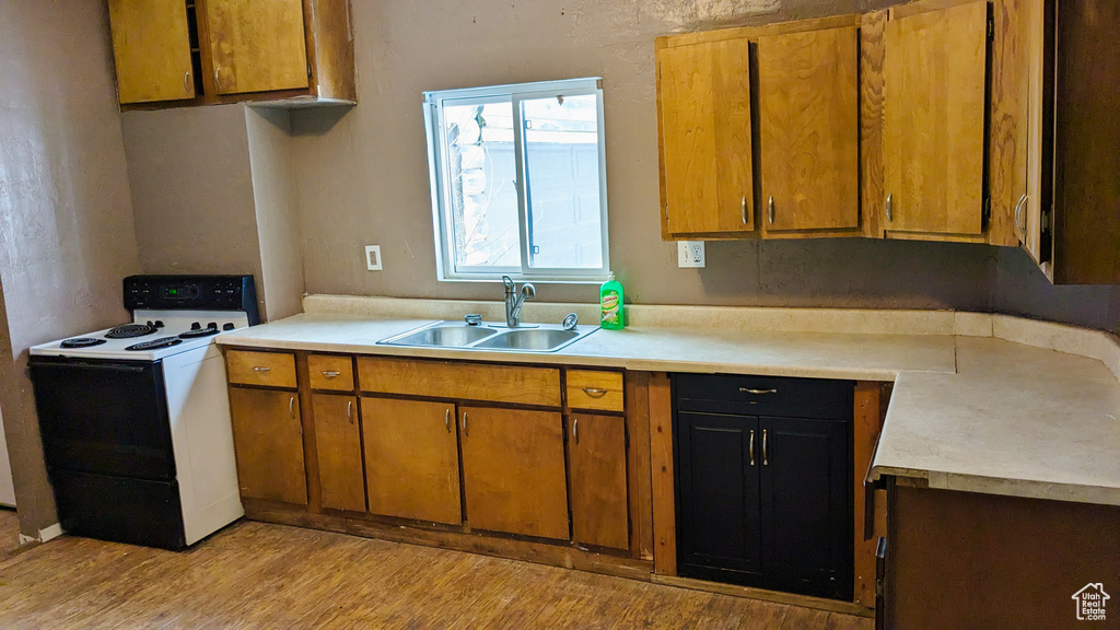 Kitchen with sink, light hardwood / wood-style flooring, and electric stove