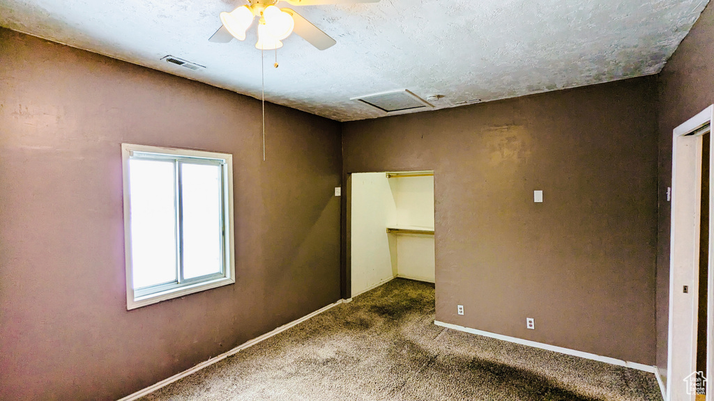 Spare room with ceiling fan, dark carpet, and a textured ceiling