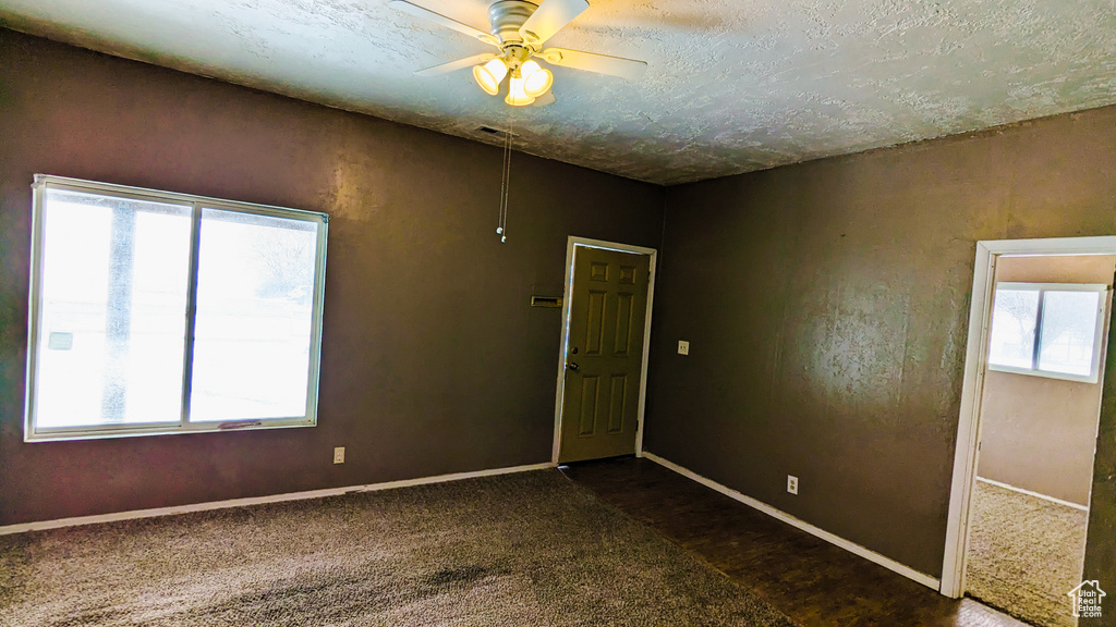 Carpeted spare room featuring ceiling fan and a textured ceiling