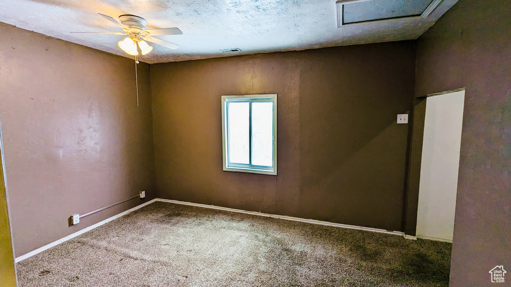 Carpeted empty room with ceiling fan and a textured ceiling