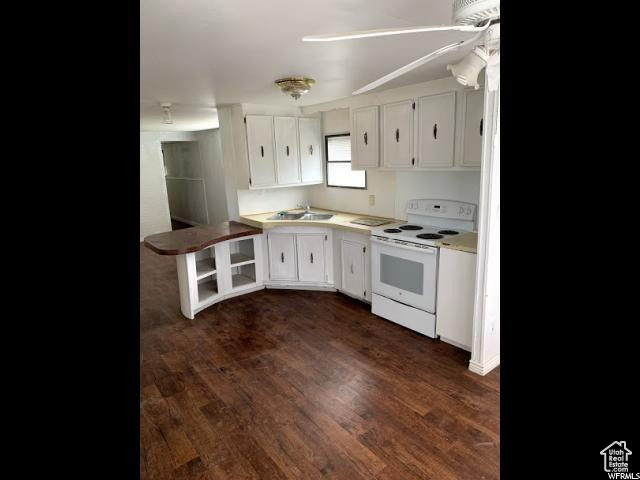 Kitchen with white electric range oven, dark hardwood / wood-style floors, white cabinetry, and sink