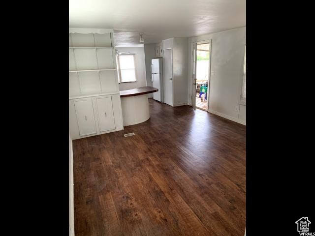 Kitchen featuring white cabinets, white fridge, and dark wood-type flooring