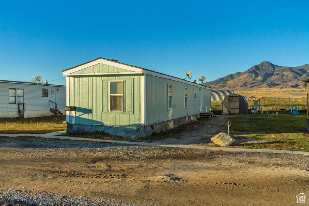 View of side of property with a mountain view and a shed