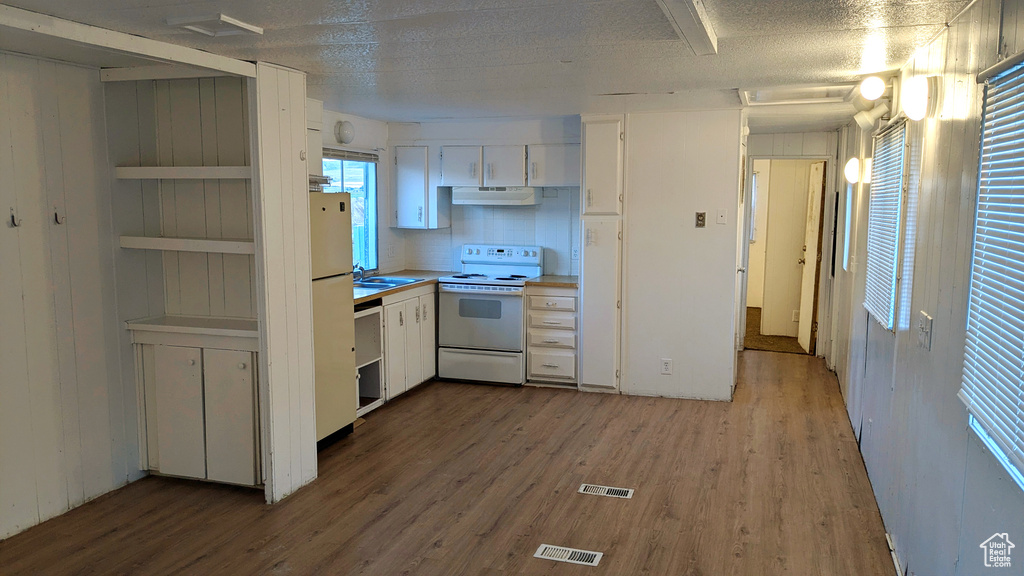 Kitchen with white appliances, a textured ceiling, sink, hardwood / wood-style floors, and white cabinetry