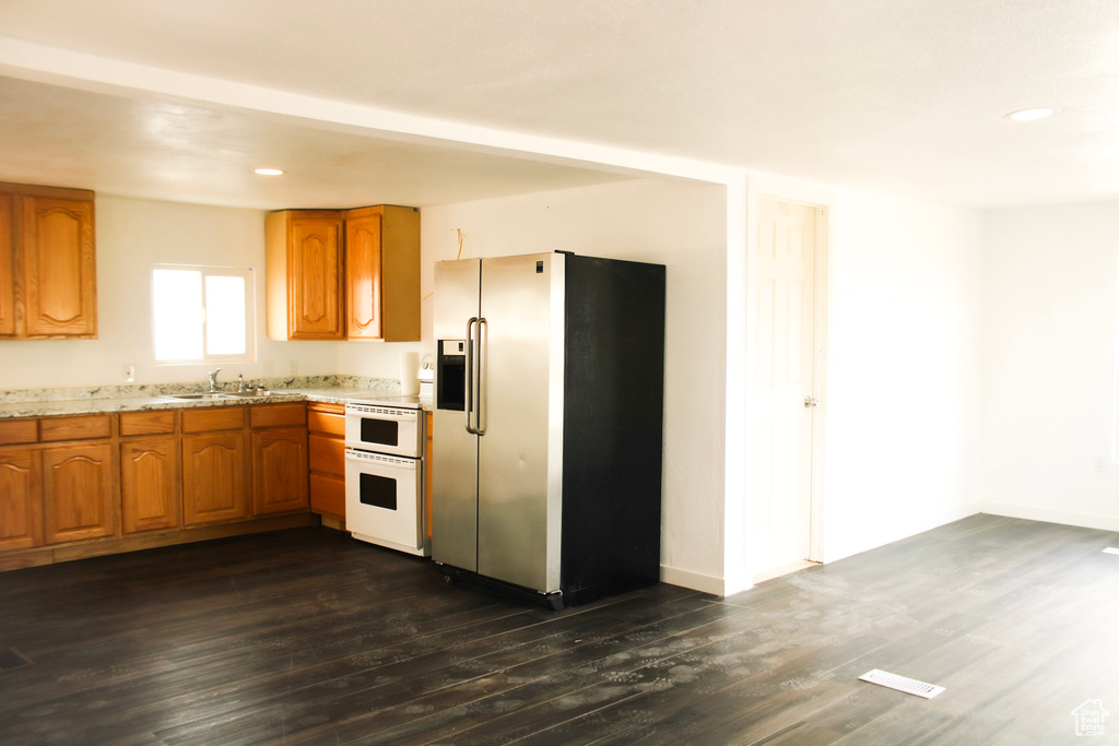 Kitchen featuring dark hardwood / wood-style floors, white range oven, stainless steel fridge with ice dispenser, and sink