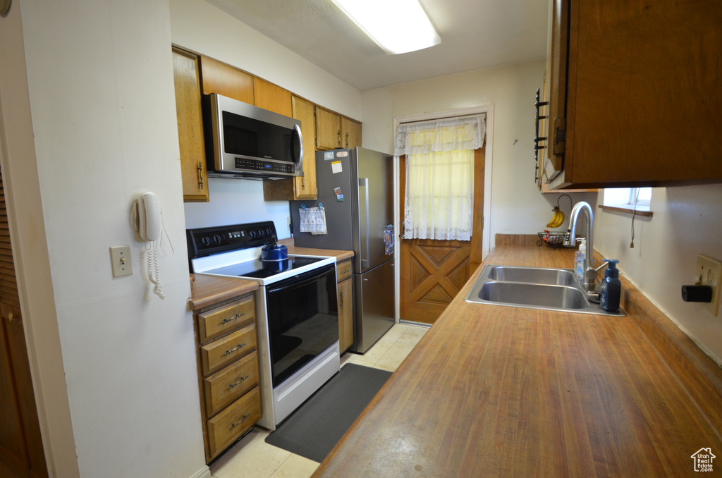 Kitchen with appliances with stainless steel finishes, light hardwood / wood-style floors, plenty of natural light, and sink