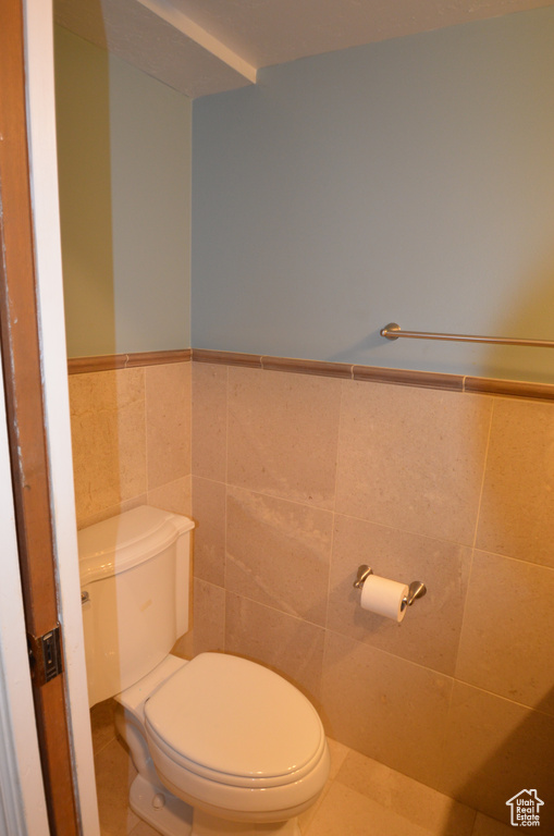 Bathroom featuring tile patterned flooring, tile walls, and toilet