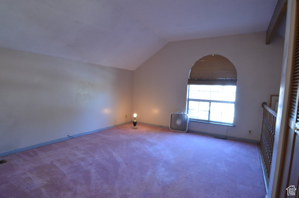 Carpeted empty room featuring vaulted ceiling