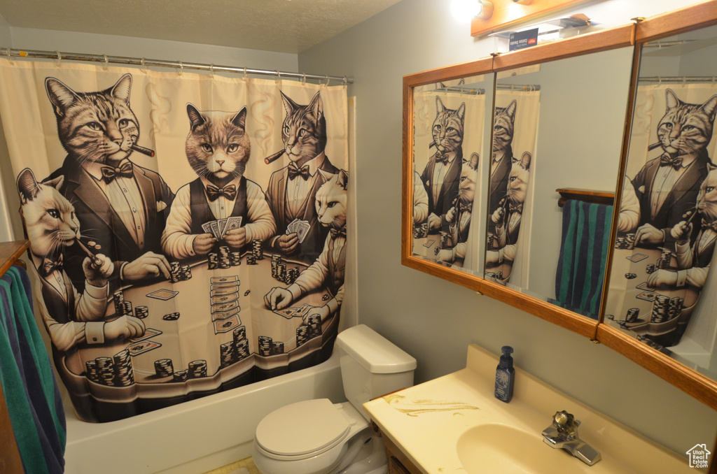 Full bathroom featuring vanity, shower / tub combo, a textured ceiling, and toilet