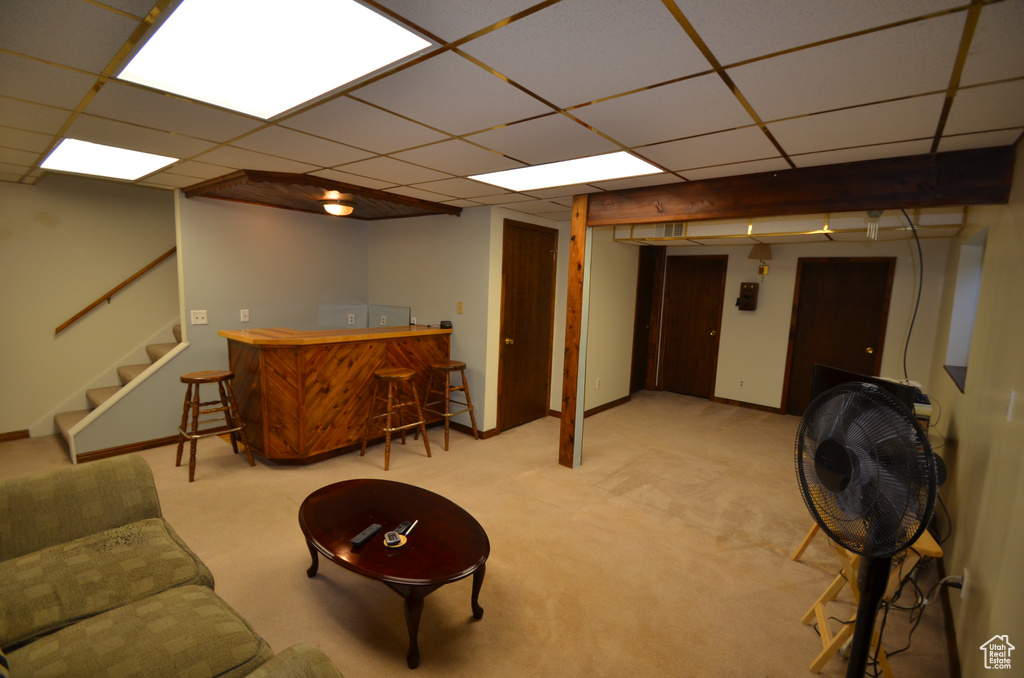 Basement featuring a paneled ceiling, light carpet, and indoor bar