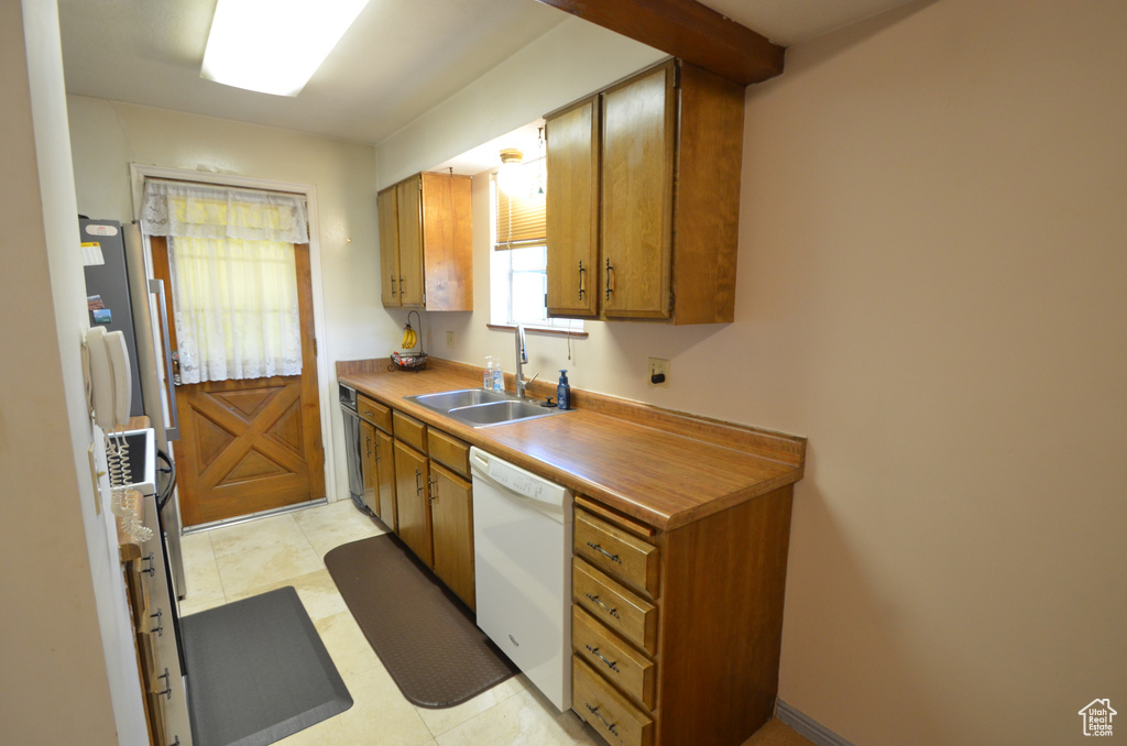 Kitchen with sink, light tile patterned floors, and white appliances