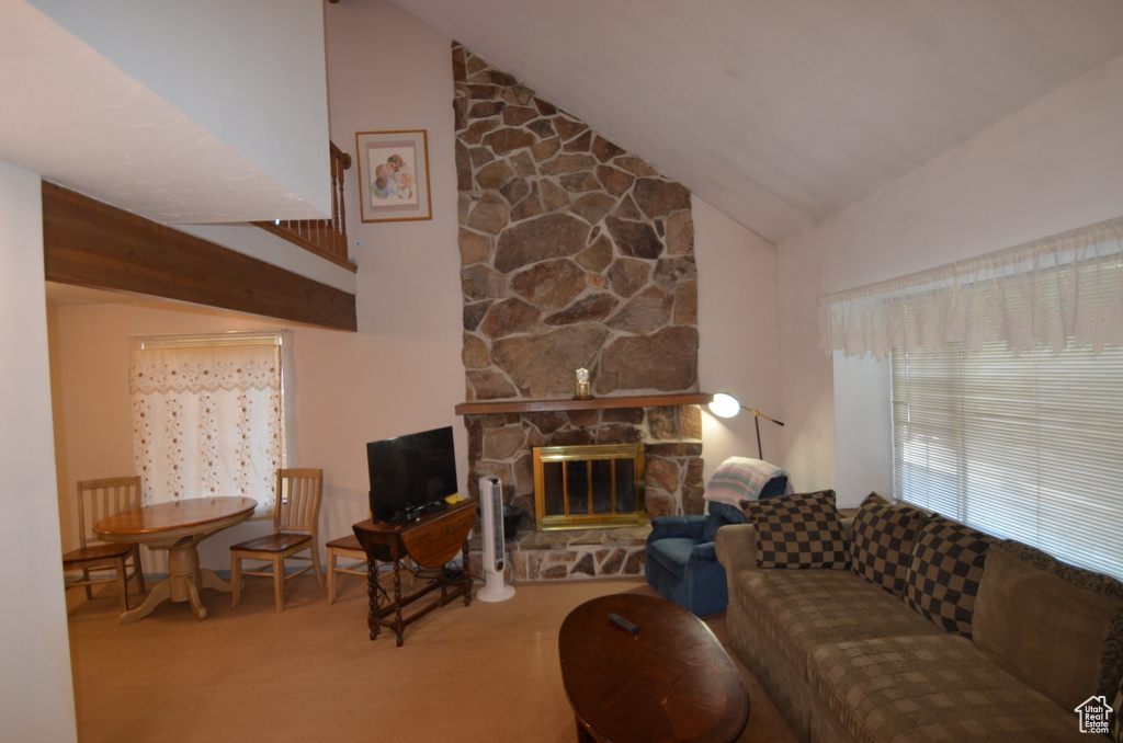 Carpeted living room with high vaulted ceiling and a stone fireplace