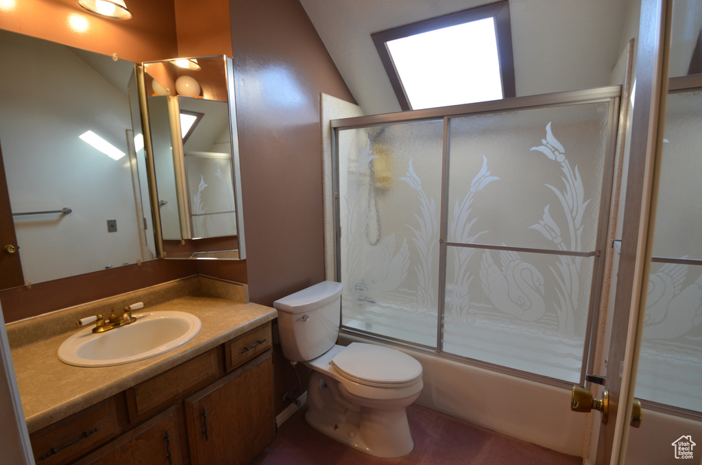Full bathroom with vanity, toilet, lofted ceiling, and enclosed tub / shower combo