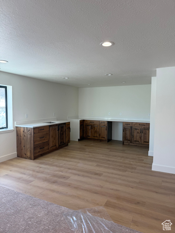 Interior space with light wood-style floors, baseboards, and a textured ceiling