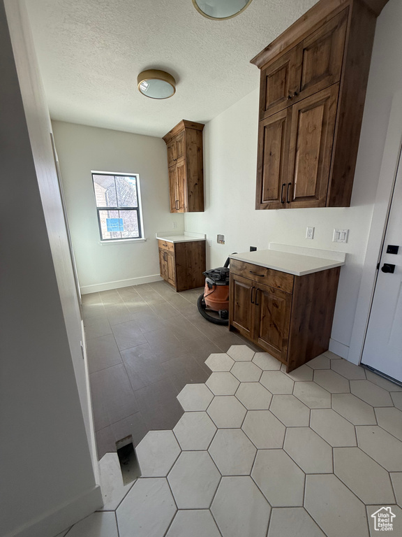 Kitchen featuring light countertops, a textured ceiling, and baseboards