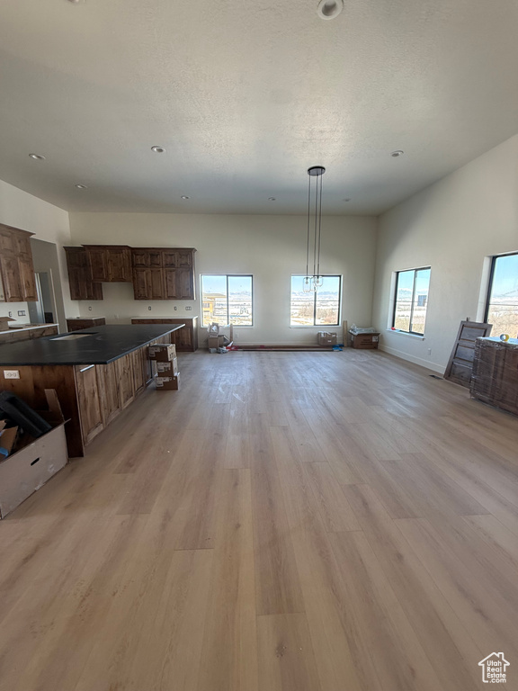 Kitchen with dark countertops, light wood-style flooring, baseboards, and open floor plan