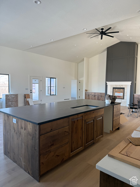 Kitchen featuring lofted ceiling, a large island, open floor plan, black electric cooktop, and a multi sided fireplace