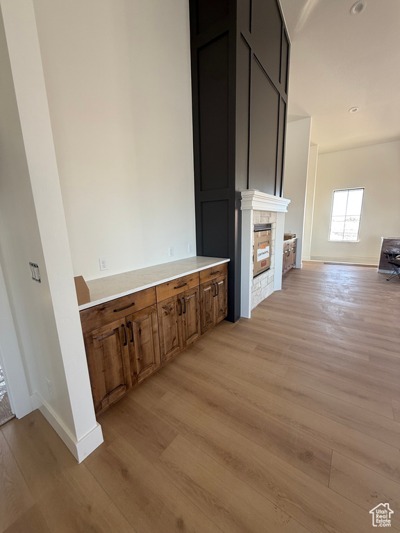 Interior space featuring light wood-style flooring, brown cabinetry, light countertops, and a stone fireplace