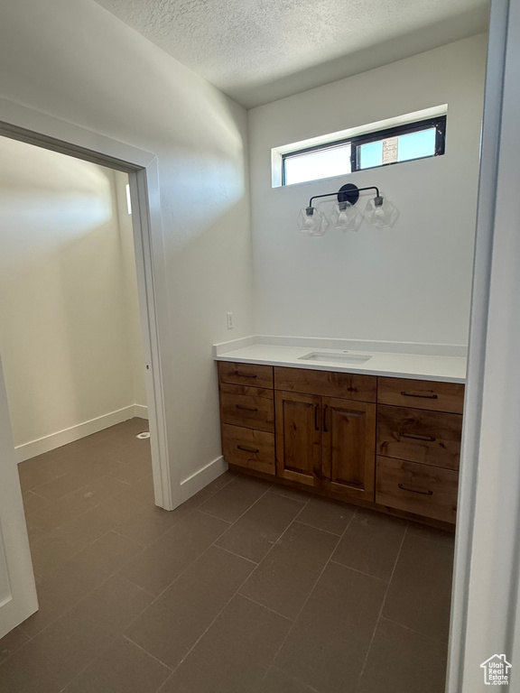 Bathroom with tile patterned floors, baseboards, a textured ceiling, and vanity