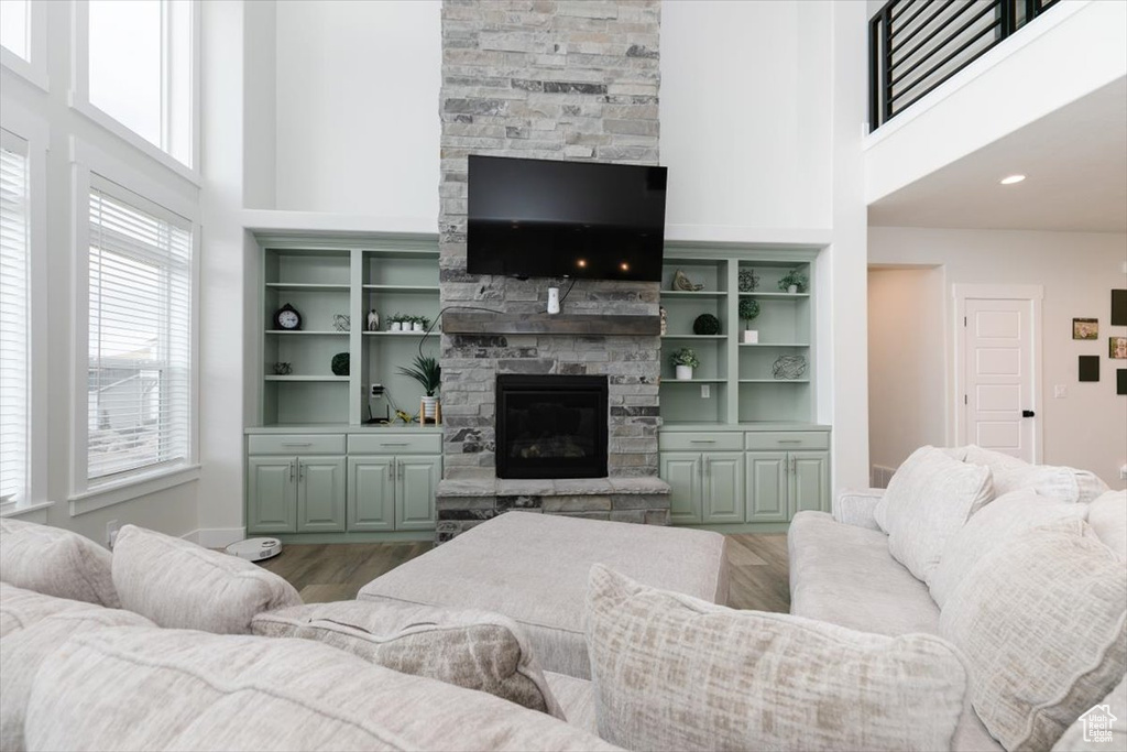 Living room with a stone fireplace, hardwood / wood-style floors, and a towering ceiling