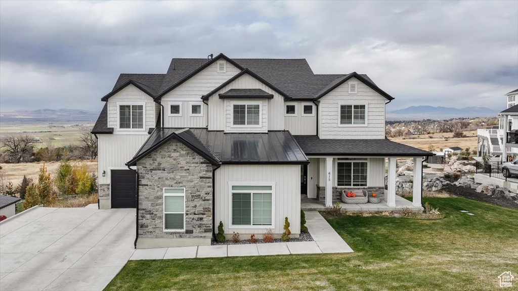 View of front of property with a mountain view, a front yard, and a garage