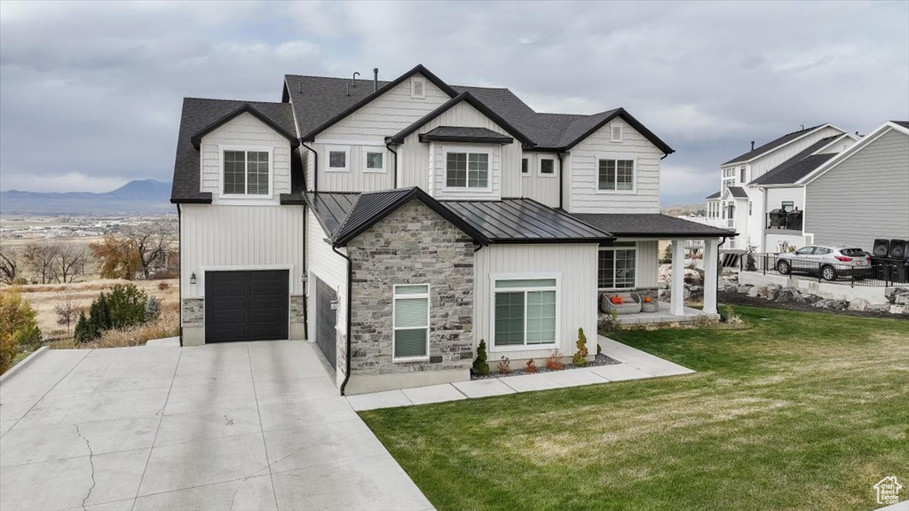 View of front facade with a mountain view, a front yard, and a garage