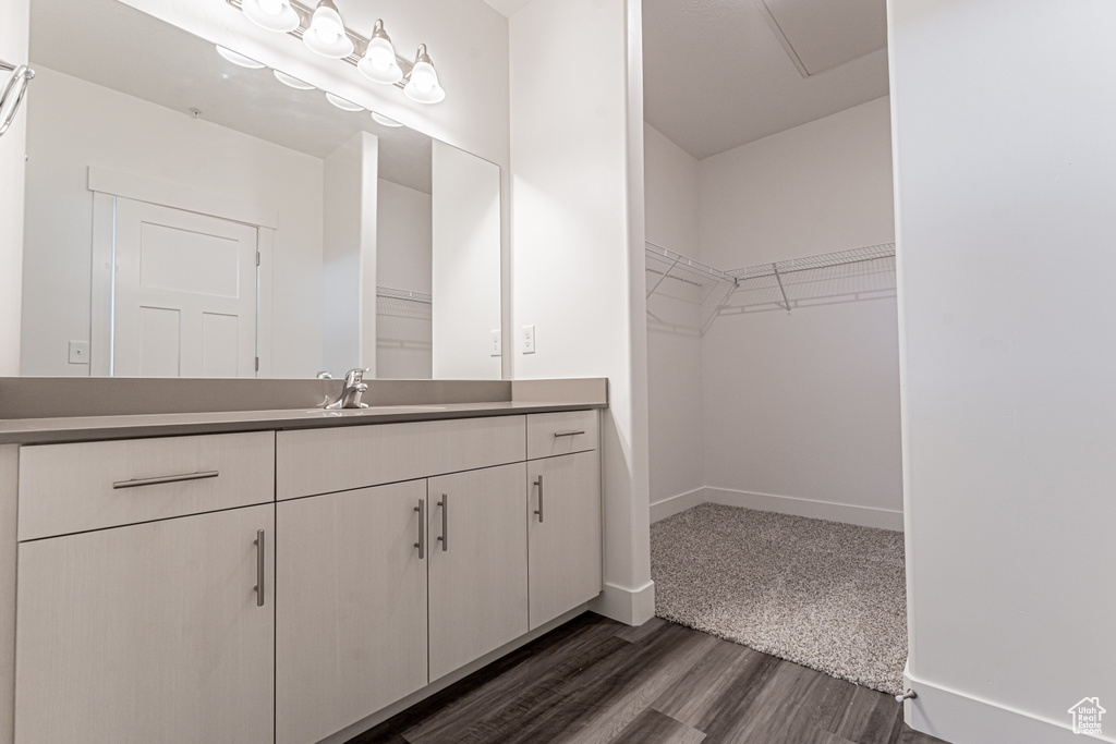 Bathroom featuring baseboards, a spacious closet, wood finished floors, and vanity