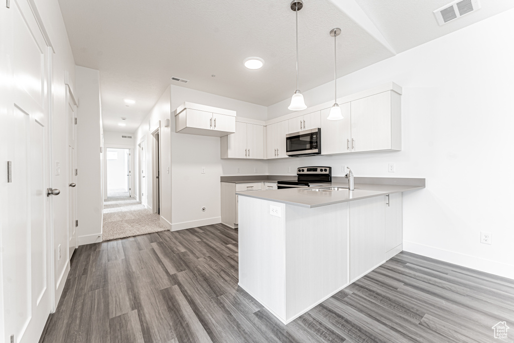 Kitchen featuring appliances with stainless steel finishes, visible vents, baseboards, wood finished floors, and a peninsula