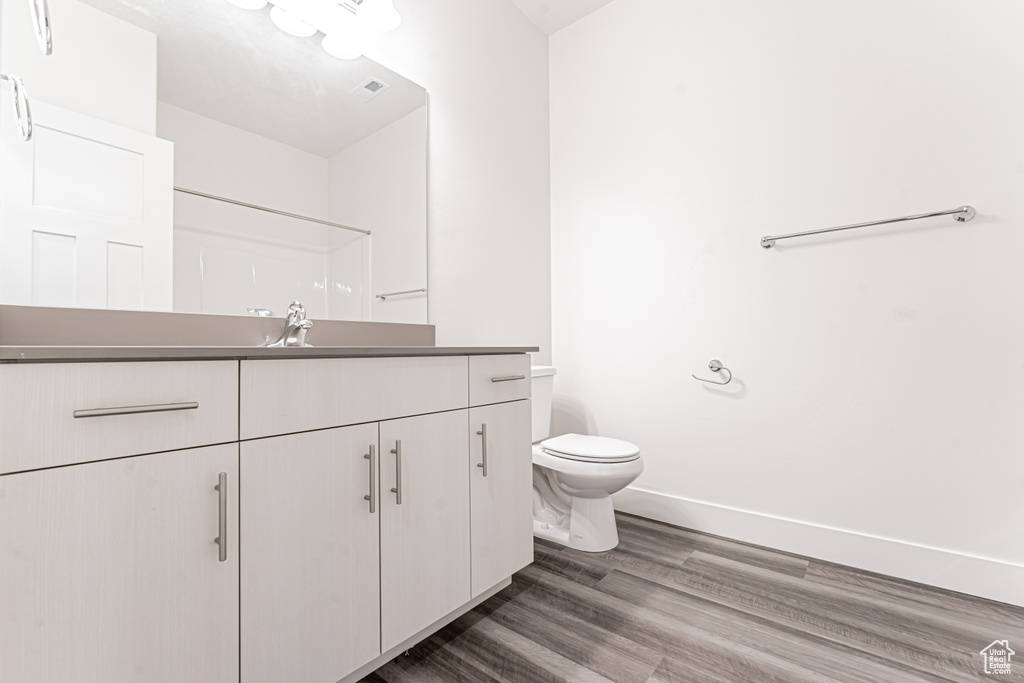 Full bath featuring toilet, wood finished floors, vanity, and baseboards