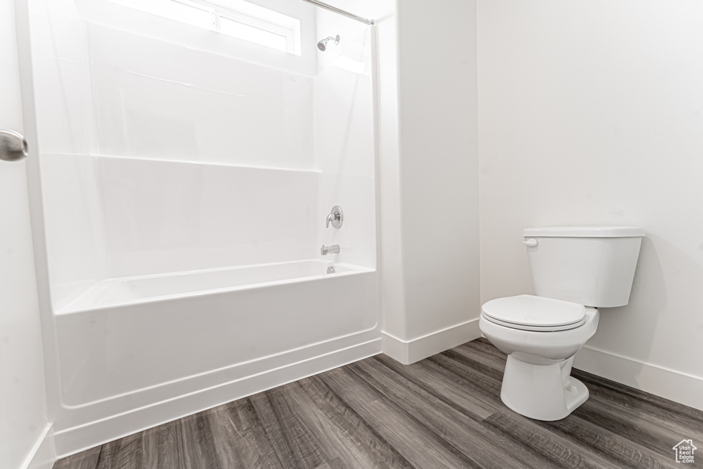 Full bathroom featuring toilet, shower / tub combination, wood finished floors, and baseboards