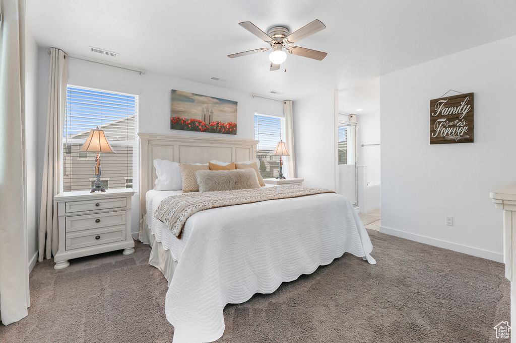 Carpeted bedroom with connected bathroom and ceiling fan