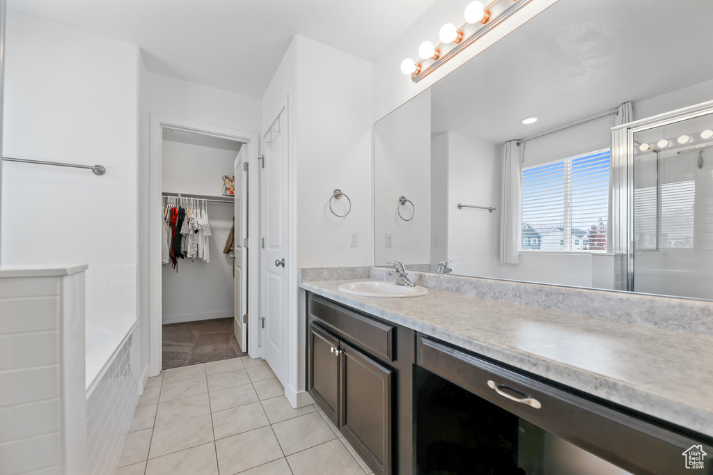 Bathroom with tile patterned flooring, shower with separate bathtub, and vanity