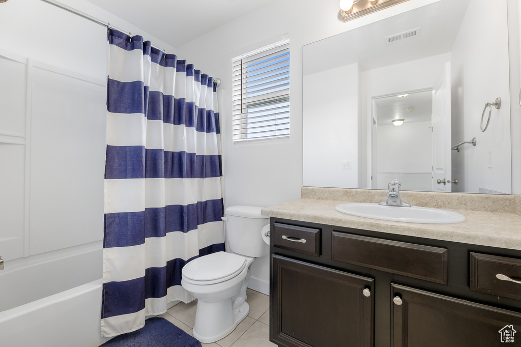 Full bathroom with tile patterned floors, shower / bathtub combination with curtain, vanity, and toilet